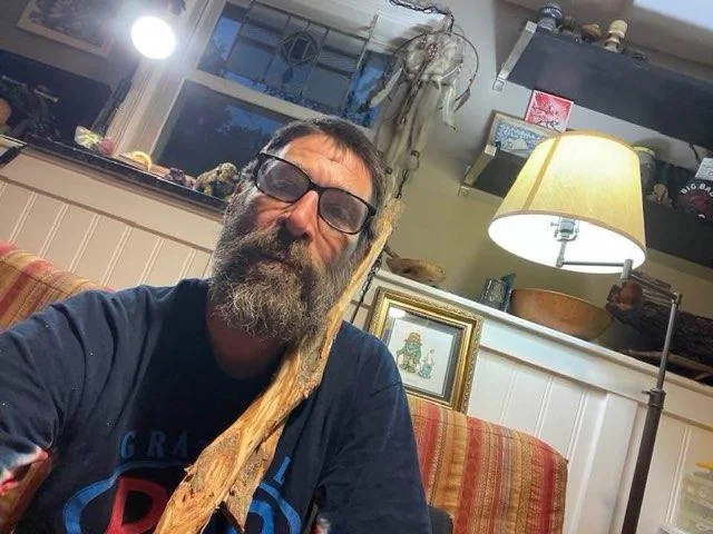 Levon Sherfield in his workshop holding a hand-carved walking stick — Knotted Wood Ranch, Spotsylvania VA